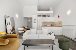 En moderne stue og spiseområde i åben plan med en hvid sofa, et træbord og et spisebord med stole.