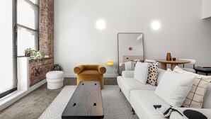 Una sala de estar moderna con sofá, otomanas, una mesita de centro y una pared decorada con ladrillos.