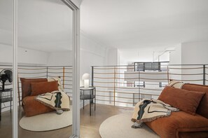 A modern living room with a sofa, a round rug, and a glass partition. - Classic 1-bed City Stay Near Eateries and Laneways (Melbourne)