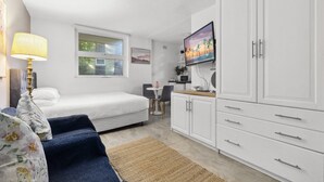 A compact bedroom with a bed, a desk, a TV, and a wardrobe. - Chic Urban Paddington Escape (Sydney)