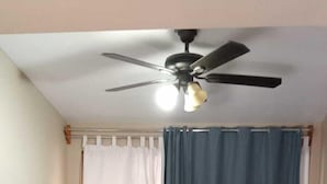 Un dormitorio con cama, ventilador de techo y cortinas.