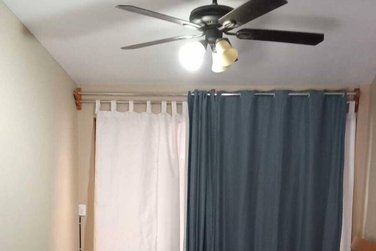 A bedroom with a bed, a ceiling fan, and curtains.