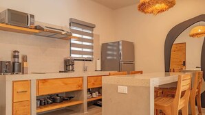 A modern kitchen with a built-in microwave, coffee maker, and stainless steel refrigerator.