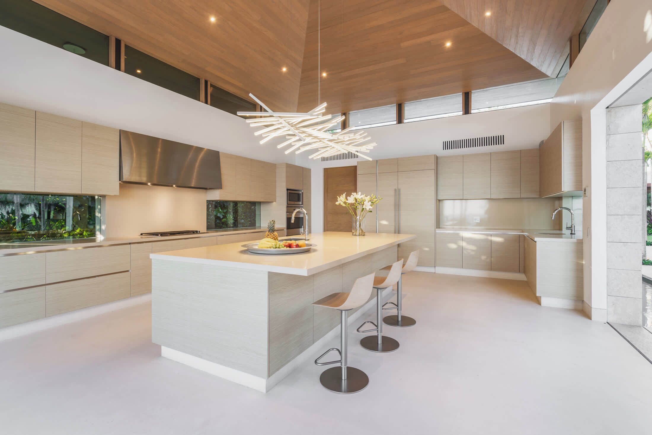 Una cucina moderna con una grande isola, sgabelli da bar e un'originale lampada a sospensione.