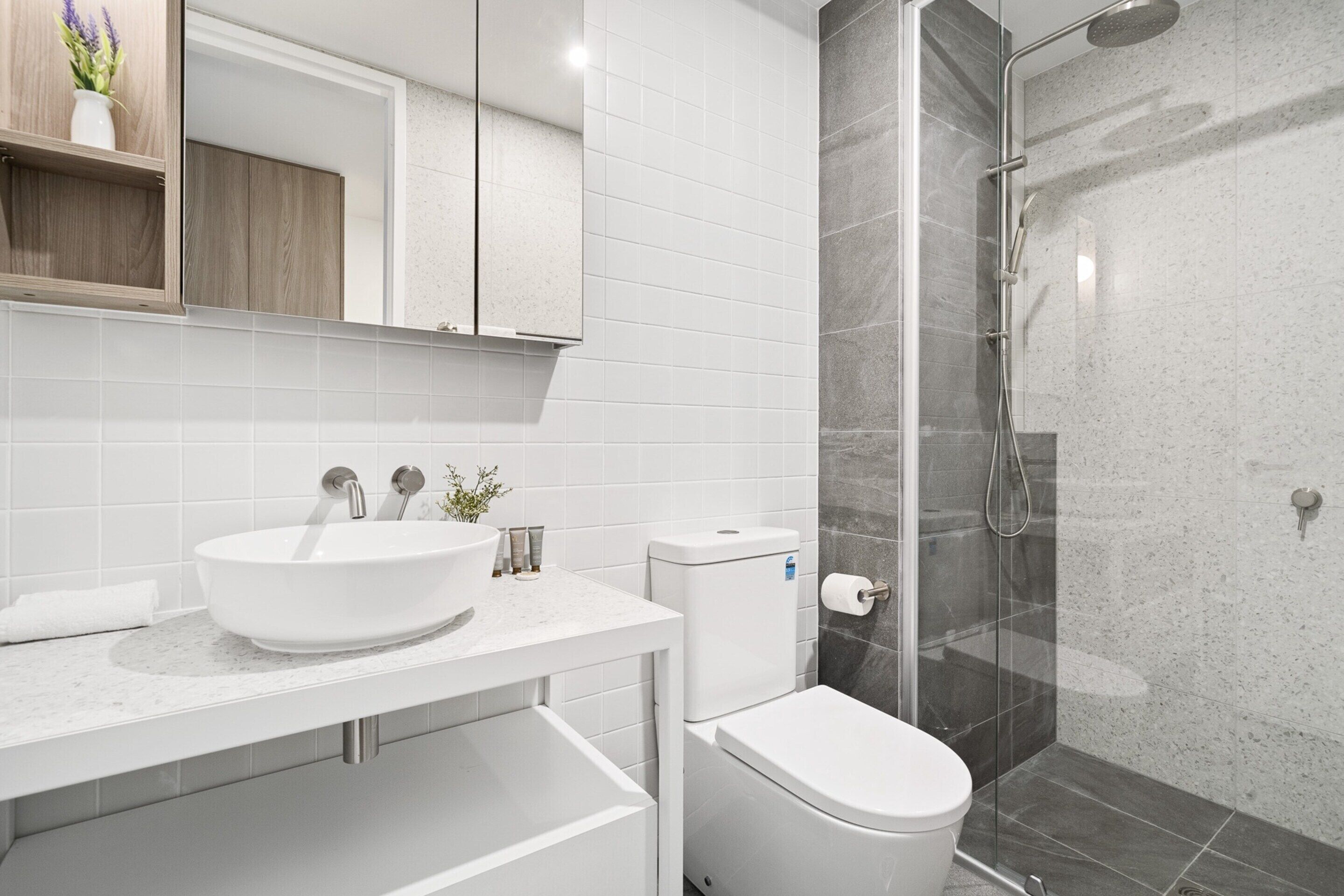 Une salle de bain moderne avec un lavabo blanc, des toilettes et une douche à parois de verre.