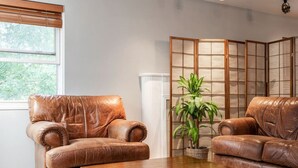 A room with two leather armchairs, a wooden coffee table, and a traditional Japanese room divider with a potted plant. - Cozy, Low-Key, Perfect for Short & Extended Visits (Salt Lake City)