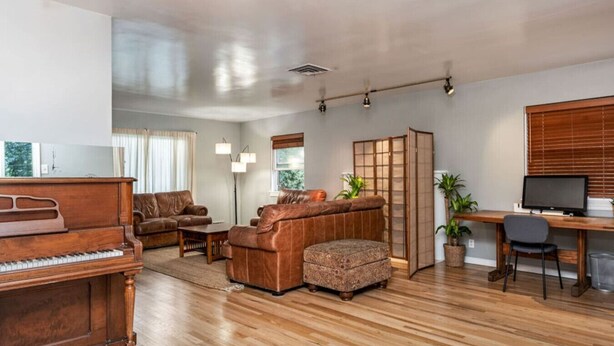 A spacious living room with a grand piano, leather sofas, a wooden coffee table, and a wooden desk with a computer. - Cozy, Low-Key, Perfect for Short & Extended Visits (Salt Lake City)