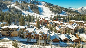 Un complejo turístico cubierto de nieve, con varios edificios, incluida una cabaña grande y un telesilla visible al fondo.