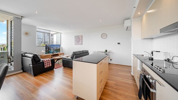 Un appartement moderne comprenant une cuisine, un coin repas et un salon. Il est doté d’une grande fenêtre, d’un téléviseur à écran plat et d’un canapé.
