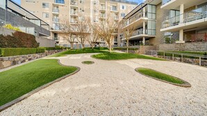 Un immeuble d’appartements moderne doté d’une cour intérieure, de murs en pierre et d’un mélange de balcons et de fenêtres.