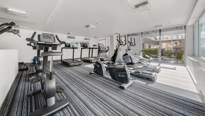 Une salle de sport moderne équipée de tapis de course, de vélos elliptiques et d’un banc de musculation.