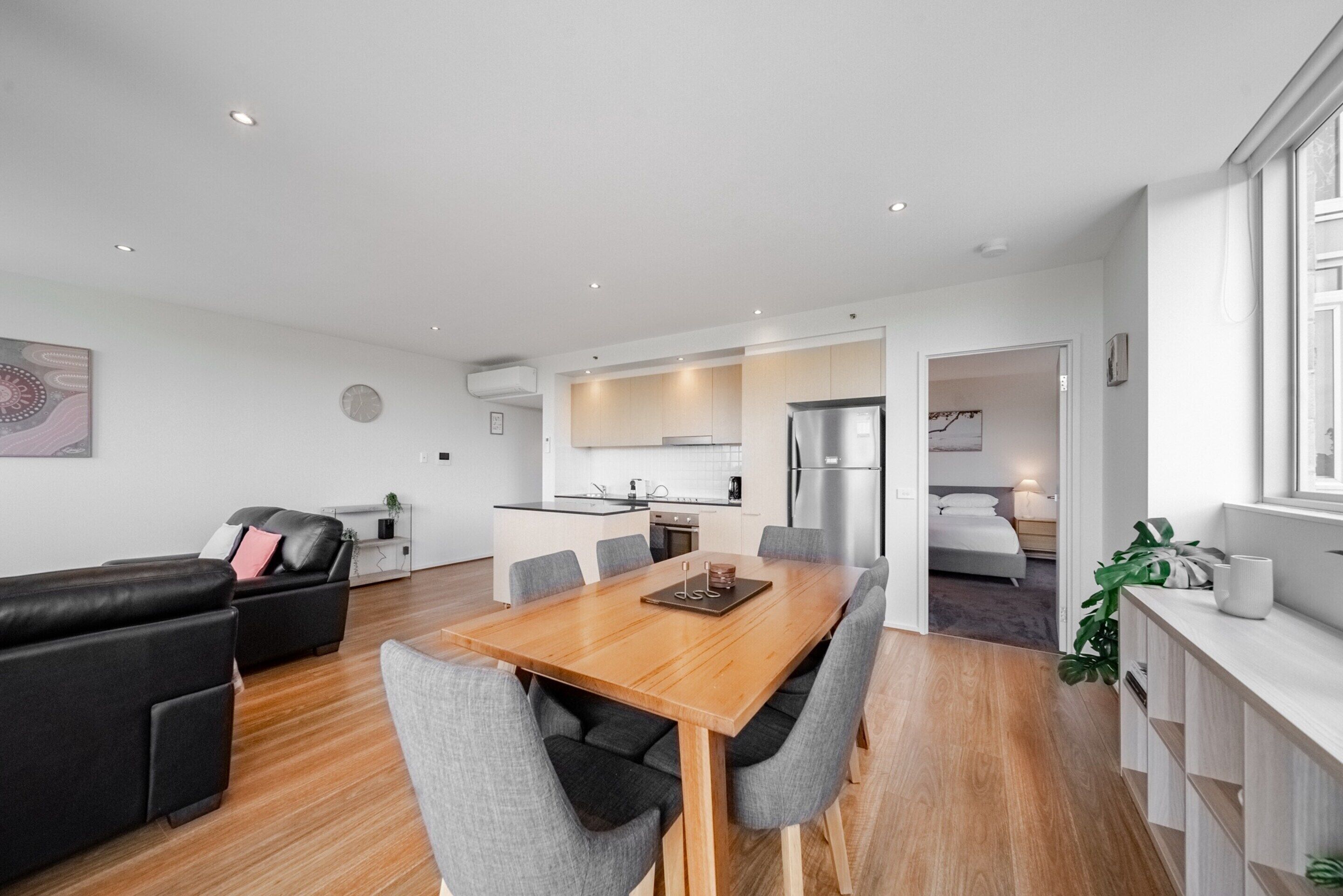 A modern apartment with a dining area, kitchen, and living room.