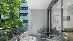 Un balcon moderne avec une balustrade en verre, une petite table et une chaise.