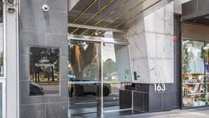 Une entrée moderne avec une porte en verre, une enseigne indiquant « Halo Apartments » et le numéro « 163 » sur le mur.
