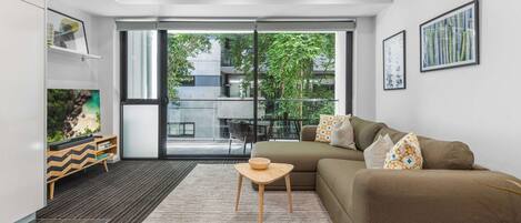 A modern living room with a sofa, a small wooden table, and a bookshelf.