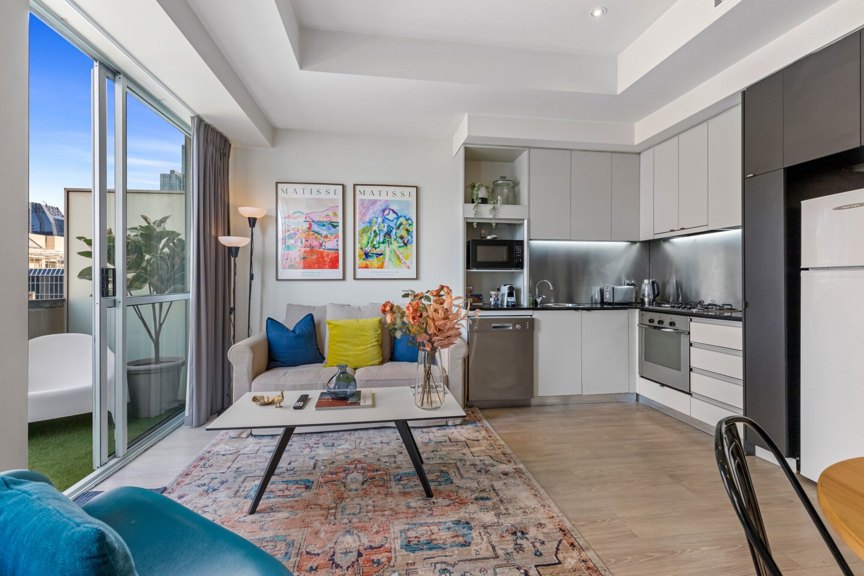A modern apartment with a living room, kitchen, and a balcony with a city view.