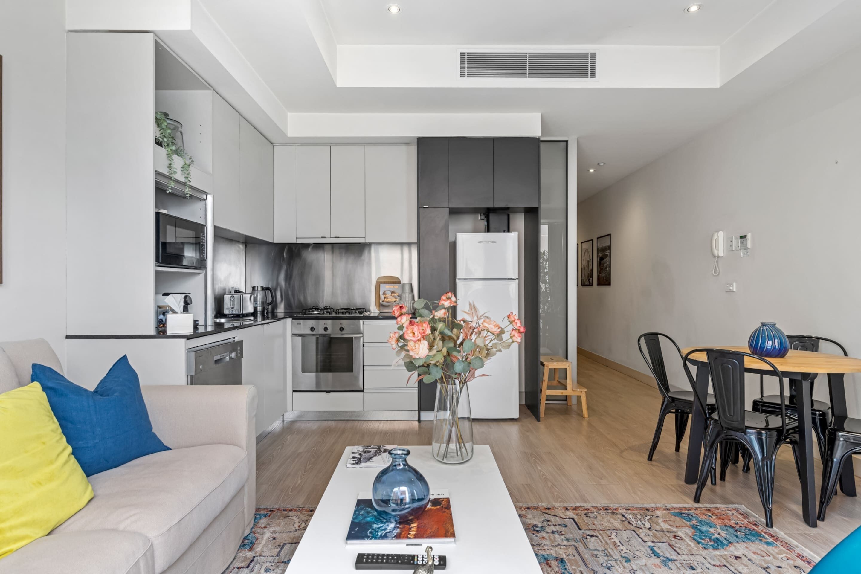 Un espace de vie moderne comprenant une cuisine, un coin repas et un canapé agrémenté de coussins.