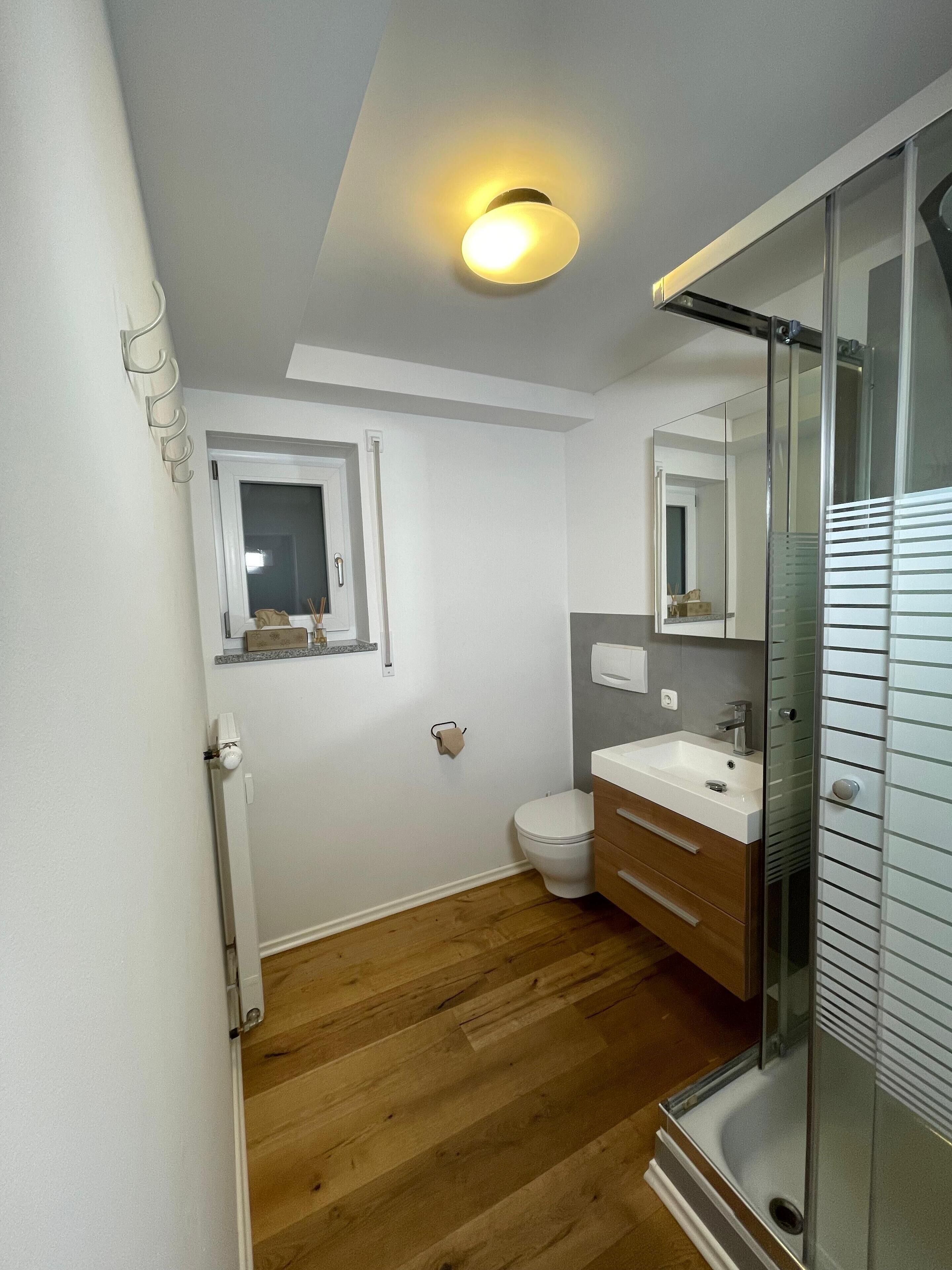 Ein modernes Badezimmer mit Toilette, Waschbecken und Dusche.