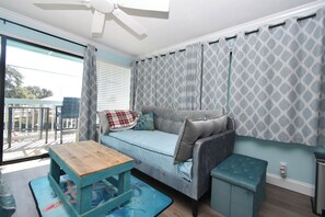 A cozy room with a sofa, a small table, and a bench. - Dolphins Cay - Pet Friendly Condo 230 (Cedar Key)