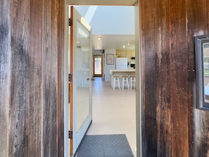 A modern kitchen with white cabinets, a white refrigerator, and a bar area with stools.