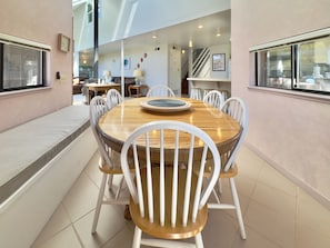 A dining area with a round wooden table, white chairs, and a bench along the wall.