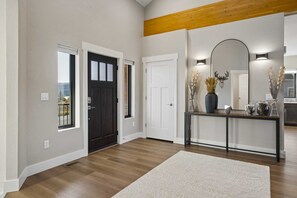 A hallway with a wooden floor, a white rug, a console table with decorative items, and a large mirror. - New built, stunning home with Hot Tub, 5/4, near Granby Ranch - sleeps 16 (Granby)