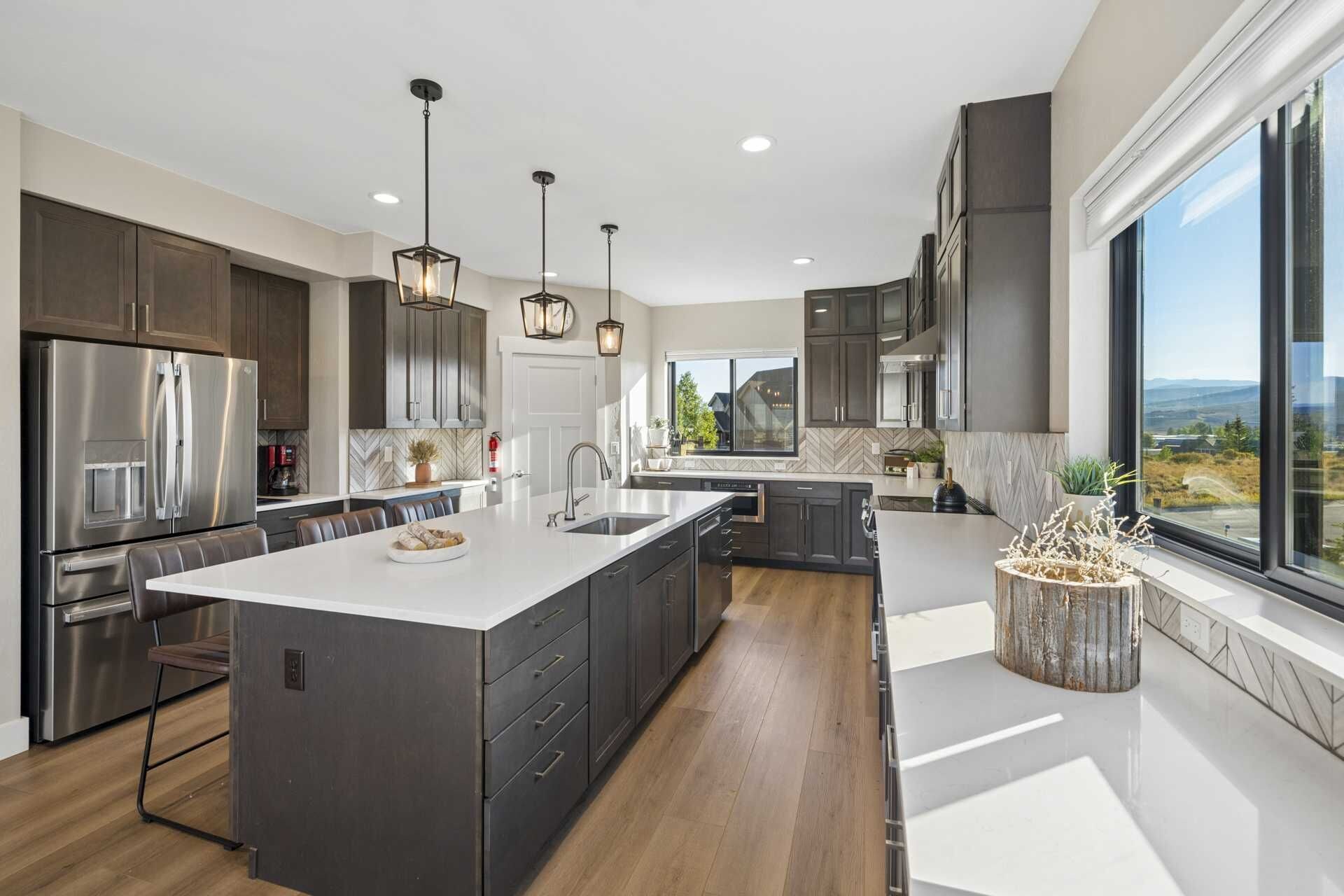 A modern kitchen with a large island, stainless steel appliances, and a view of the outdoors.