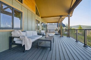 A covered outdoor seating area with a sofa and table, overlooking a residential area. - New built, stunning home with Hot Tub, 5/4, near Granby Ranch - sleeps 16 (Granby)
