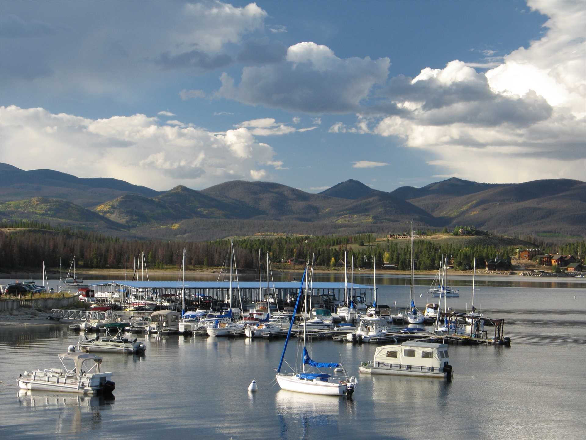 Un puerto deportivo con barcos amarrados, rodeado de montañas y un cielo despejado.
