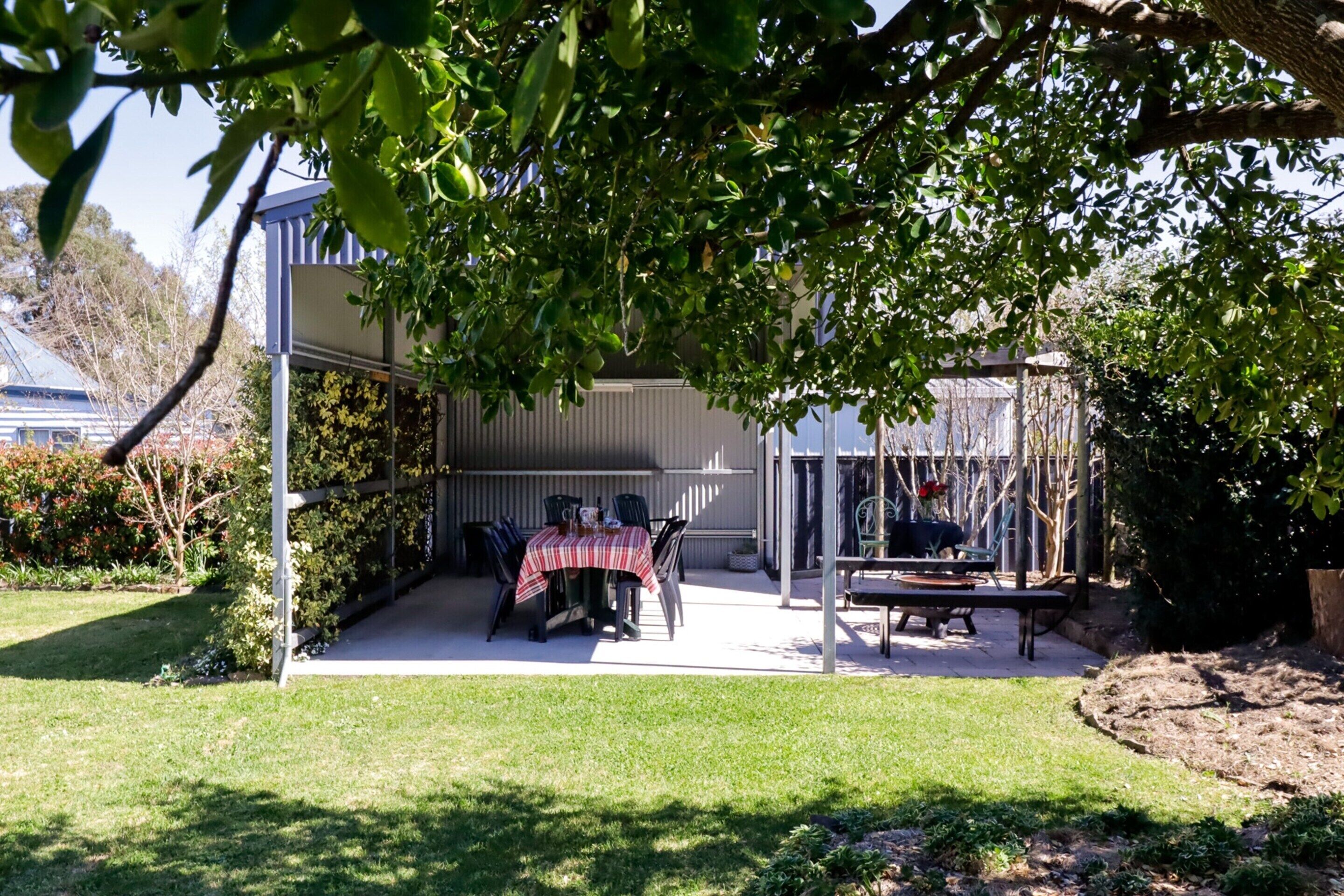 A patio area with a table and chairs, a covered seating area, and a view of a building in the background.