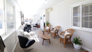 A bright hallway with wicker furniture, a wooden table, and potted plants. - Heritage Home With BBQ & Outdoor Fire Pit (Tenterfield)