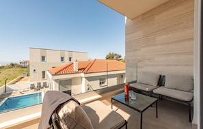 Uma varanda com piscina, sofá e mesa.
