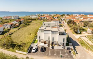 Zona residencial con edificios modernos, un estacionamiento y vista al mar.