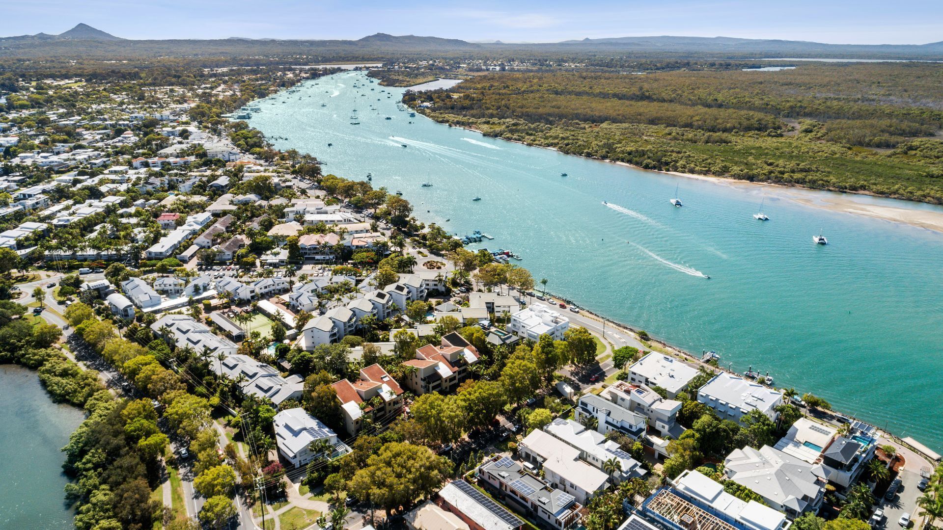 Vista aérea de una zona residencial costera con casas, un puerto deportivo y un río.