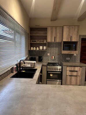 A modern kitchen with a built-in stove, oven, and microwave. There are wooden cabinets and a herringbone-patterned backsplash.