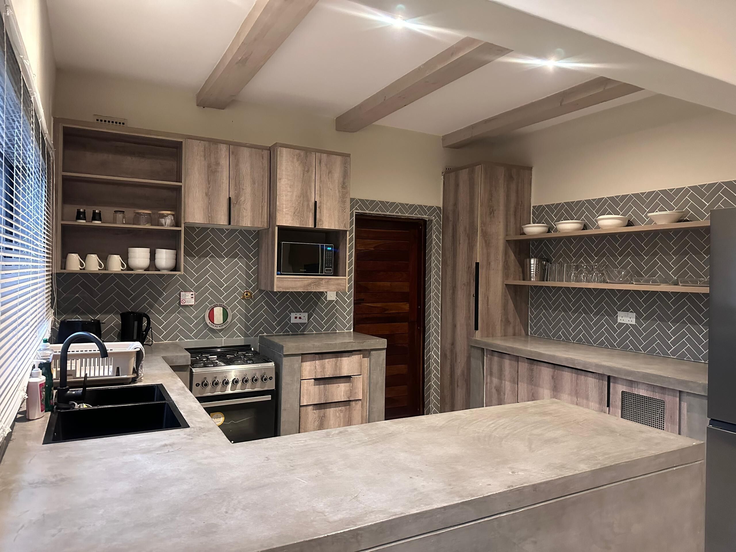 Une cuisine moderne avec des meubles en bois, un four à micro-ondes encastré et une cuisinière en acier inoxydable.