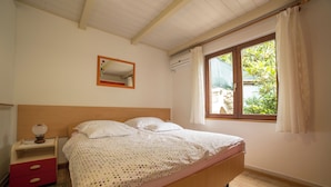 Une chambre à coucher avec un lit en bois, une table de chevet, un miroir et une fenêtre avec des rideaux.