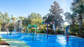 Zona de juegos acuáticos al aire libre con estructuras coloridas y un camino pavimentado.