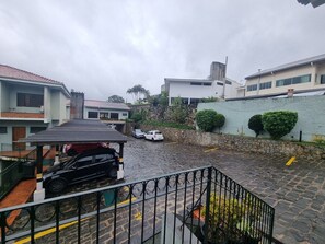 Zona residencial con patio empedrado, cochera techada y muro de piedra.
