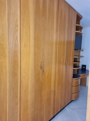 A wooden wardrobe with multiple doors and a built-in shelf unit. - Lindo loft decorado centro com garagem  (São Roque)