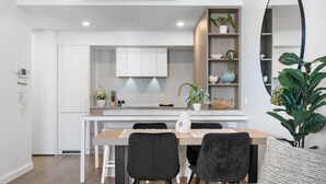A modern kitchen with white cabinets, a wooden countertop, and a built-in shelf with plants. - Charming 1-bed With Rooftop Access & Parking (Perth)