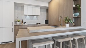 A modern kitchen with a central island, bar stools, and built-in cabinets. - Charming 1-bed With Rooftop Access & Parking (Perth)