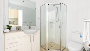 A modern bathroom with a glass-enclosed shower, a white sink, and a toilet.