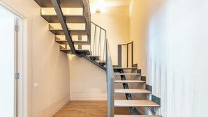 A modern staircase with a metal railing and wooden steps, leading to an upper floor. - Studio in the center of Porto for tourism or remote work (Porto)
