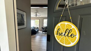 Un pasillo que conduce a un salón con una puerta que tiene un cartel que dice 'hello'.