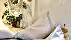 A cozy seating area with white cushions and a woven basket. - Corais Do Sul (Porto Seguro)