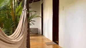 A hallway with a hammock, a wooden floor, and a door. - Corais Do Sul (Porto Seguro)