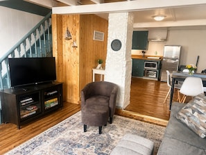 A living room with a television, a sofa, a coffee table, and a rug.