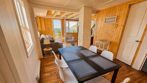 A room with a wooden floor, a table with chairs, a sofa, and a view of the sea. - Bishop's Landing (Portugal Cove-St. Philip's)