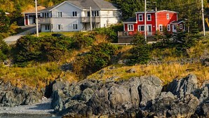 A coastal house with a dock, surrounded by rocky shoreline and dense forest. - Bishop's Landing (Portugal Cove-St. Philip's)